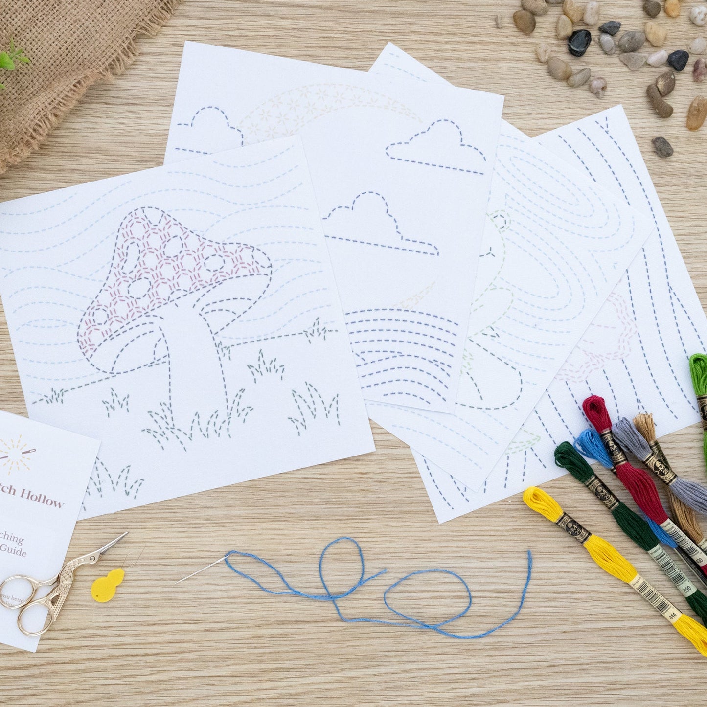 Sashiko-inspired Embroidery Sheets displayed on a wooden board. Mushroom in field, Moon over waves, Frog on Pond and Flower in night sky.