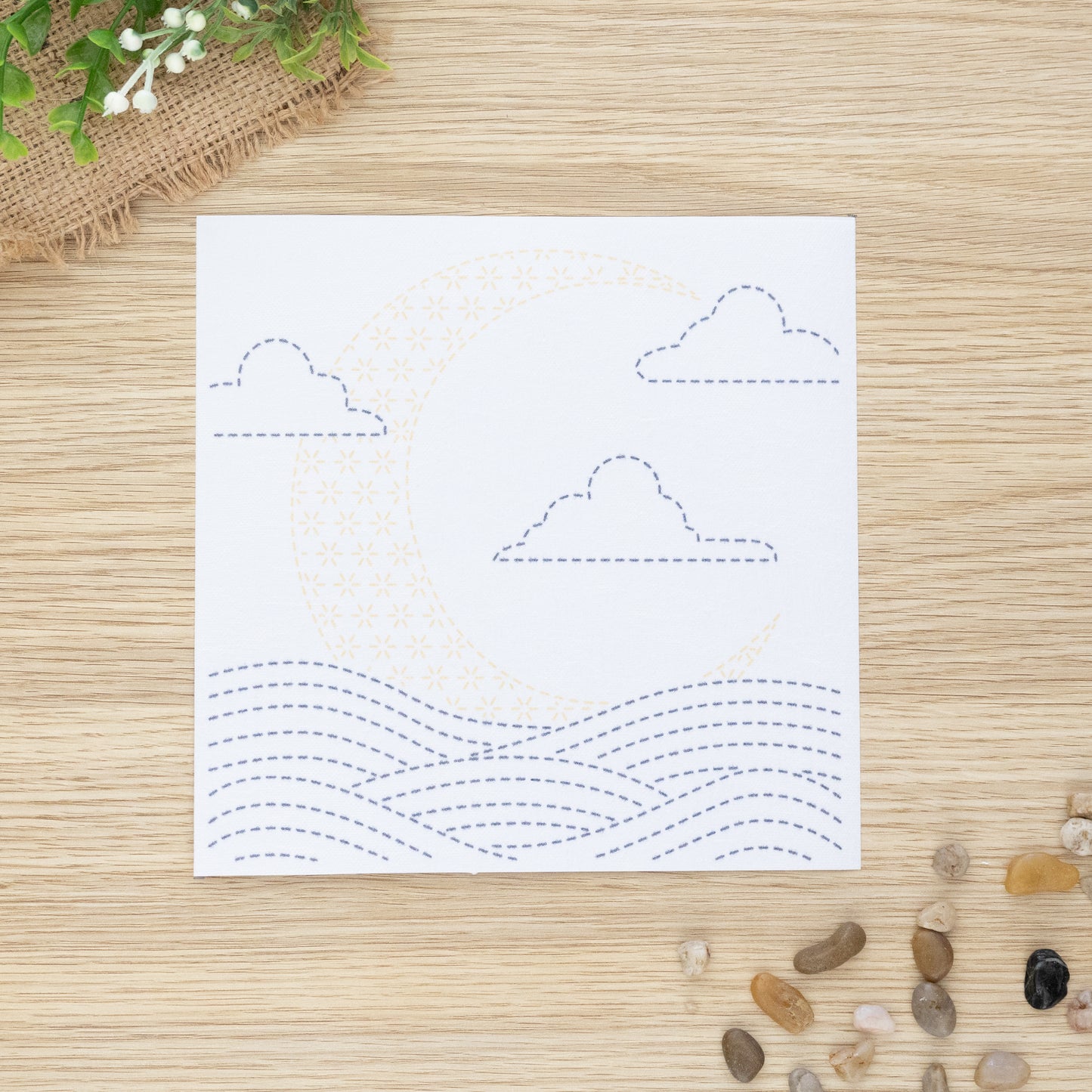 Sashiko embroidery transfer sheet of moon over waves, displayed on wooden background
